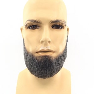 May include: A mannequin head with a short, dark gray beard. The mannequin has a neutral expression and is wearing a light brown skin tone.