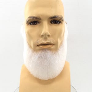 Op de afbeelding: Een witte nepbaard op een mannequinhoofd. De baard is dik en pluizig en bedekt de kin en nek van de mannequin.