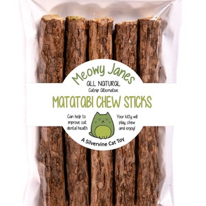 May include: A clear plastic bag containing five brown wooden sticks labeled "Meowy Janes All Natural Catnip Alternative Matatabi Chew Sticks". The label also features a cartoon cat and the text "Can help to improve cat dental health. Your kitty will play chew and enjoy! A Silvervine Cat Toy."