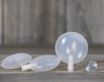 May include: Three clear plastic dog squeaky toys. One is round and the other two are oval shaped. The toys are next to a US quarter for size comparison.