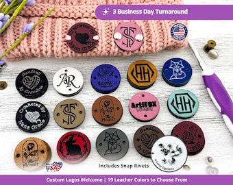 May include: A collection of round, custom-engraved leather tags in various colours, featuring designs like yarn balls, foxes, rabbits, and monograms. The tags include pre-punched holes for attachment, with metal snap rivets shown as accessories.
