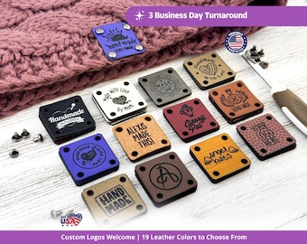 May include: A collection of square leather tags in various colours including blue, black, tan, and brown, featuring engraved text and logos such as Handmade, Made with Love, and custom designs. Each tag has four corner holes for attachment with metal rivets.