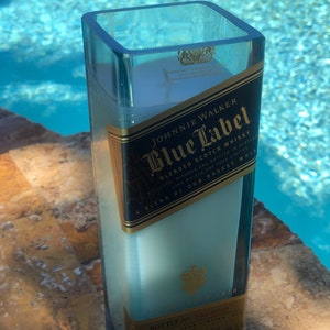 May include: A clear glass candle holder with a blue label that reads "JOHNNIE WALKER Blue Label Blended Scotch Whisky" and "A blend of our rarest whiskies".