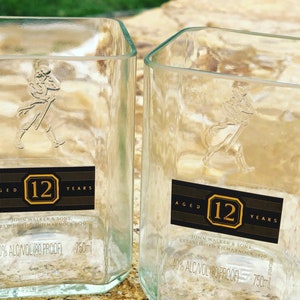 Op de afbeelding: Twee doorzichtige glazen flessen met een zwart etiket waarop "Aged 12 Years" en "John Walker & Sons. Established Kilmarnock 1820" staat. De flessen zijn 750 ml en hebben een alcoholpercentage van 40%.