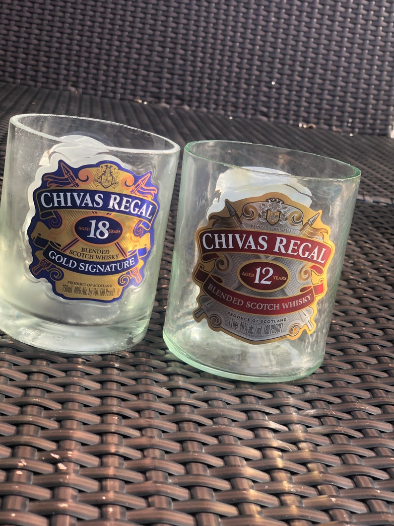 May include: Two empty glass bottles with Chivas Regal labels. The bottle on the left is labelled "Chivas Regal 18 Aged 18 Years Blended Scotch Whisky Gold Signature" and the bottle on the right is labelled "Chivas Regal 12 Aged 12 Years Blended Scotch Whisky".