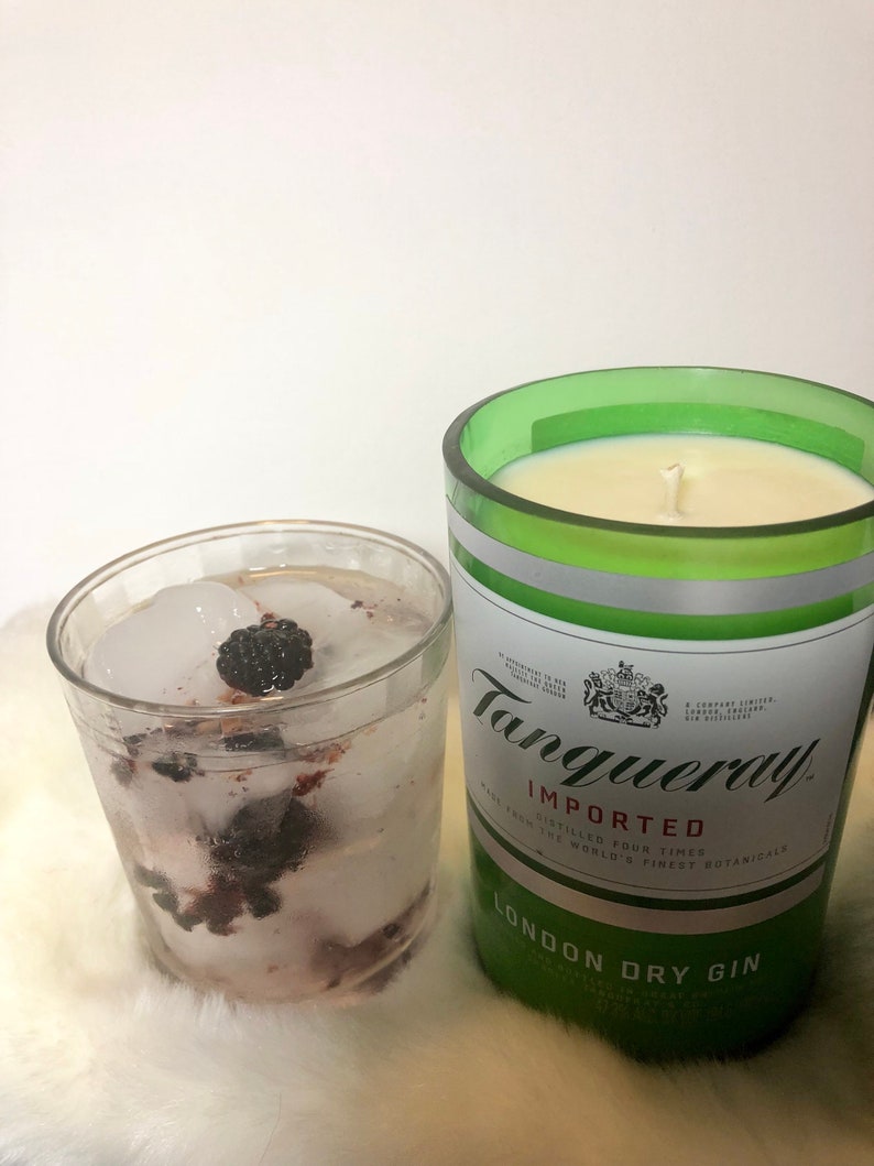 K&ouml;nnte beinhalten: Ein Glas Gin Tonic mit Eis und Brombeeren neben einer gr&uuml;nen Glasflasche Tanqueray London Dry Gin.