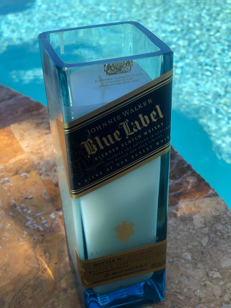May include: A blue glass candle holder shaped like a Johnnie Walker Blue Label whiskey bottle. The label reads "Johnnie Walker Blue Label Blended Scotch Whisky" and "A blend of our rarest whiskies".