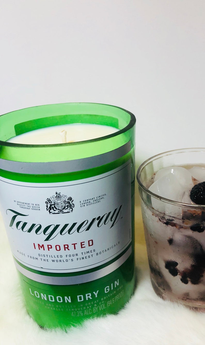 K&ouml;nnte beinhalten: Eine gr&uuml;ne Glaskerze in Form einer Tanqueray Gin-Flasche. Die Kerze hat ein wei&szlig;es Etikett mit dem Tanqueray-Logo und dem Text "Importiert, Vierfach Destilliert, Hergestellt aus den feinsten Botanicals der Welt, London Dry Gin, Abgef&uuml;llt in Gro&szlig;britannien f&uuml;r Charles Tanqueray & Co., 47,3% Alc. Vol. (94,6 Proof)".