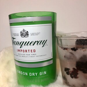K&ouml;nnte beinhalten: Eine gr&uuml;ne Glasflasche Tanqueray Imported London Dry Gin. Die Flasche hat ein silbernes Etikett mit dem Tanqueray-Logo und dem Text "Imported, Distilled Four Times, Made from the World's Finest Botanicals, London Dry Gin, 37.5% Alc. By Vol. 194.6 Proof".