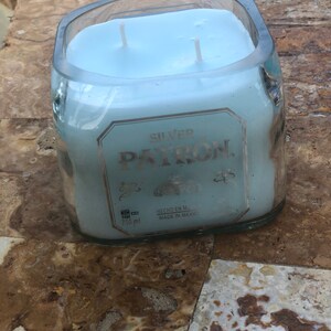 May include: A blue candle in a clear glass bottle with the label "SILVER PATRON" and "HECHO EN M. MADE IN MEXICO".