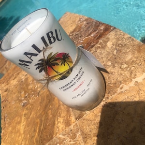 May include: A white candle in a glass jar with a Malibu label. The label features a palm tree and the text "Caribbean Rum with Coconut Liqueur - Original - 21% Alc/Vol 750 ml Imported".