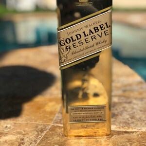 May include: A gold bottle of Johnnie Walker Gold Label Reserve Blended Scotch Whisky. The bottle has a label with the text "The Master Blender's Reserve" and "Limited Edition Bottle".