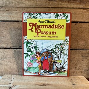 May include: A book titled "Pixie O'Harris's Marmaduke the Possum in the cave of the gnomes" with a colorful illustration of a possum, a gnome, and a bird on the cover.