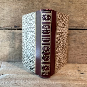 May include: A burgundy hardcover book with gold lettering on the spine. The title is "Tales from the Decameron" by Boccaccio. The book is a collector's edition.