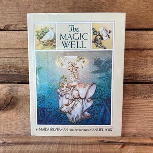 May include: The Magic Well book cover features a colorful illustration of a woman and child floating in a well with a blue sky and green trees. The title "The Magic Well" is printed in black letters on a white background. The book is by Maida Silverman and illustrated by Manuel Boix.