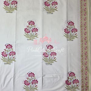 May include: A white fabric featuring a repeating pattern of magenta and green floral motifs. The design includes a decorative border with small pink flowers and green leaves. The text PinkCityArtCraft is printed in the center of the fabric.