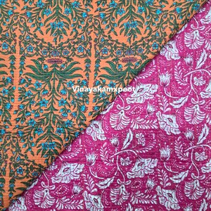Op de afbeelding: Twee stofstalen met bloempatronen. Eén is oranje met blauwe en groene bloemmotieven. De andere is magenta met witte bloemmotieven. De stoffen hebben een gewatteerde textuur.