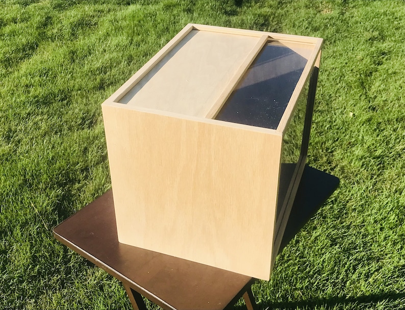 May include: A wooden box with a glass front. The box is light brown and has a simple design.