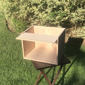 May include: A light wood box with a hinged lid and a shelf inside. The box is sitting on a dark wood table.