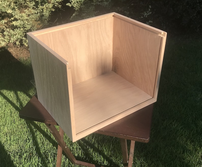 May include: A light wood box with a rectangular shape. The box is open and empty, showing the inside of the box.