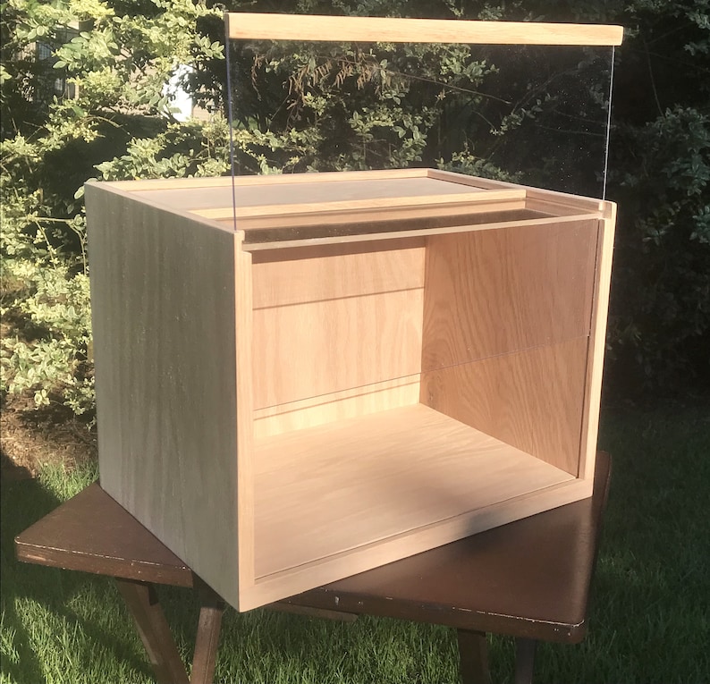 May include: A wooden display case with a clear glass top and shelves. The case is made of light wood and has a natural finish.