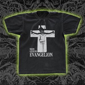 May include: Dark gray t-shirt featuring a white graphic of a figure on a cross. The text "NEON GENESIS EVANGELION" is printed below the graphic. The shirt has a crew neck and short sleeves.
