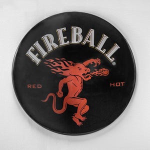 以下が含まれることがあります： 「FIREBALL RED HOT」という文字と、炎を吐く赤い悪魔の漫画が描かれた黒と赤の丸いステッカーです。