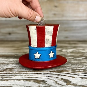 Hucha con sombrero de EE. UU. – Hucha patriótica de aluminio fundido – Decoración americana con sombrero del Tío Sam, portamonedas resistente – Envío rápido y gratuito