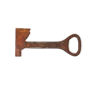 May include: Rusty metal bottle opener shaped like an axe with the words "Dixie Beer Co." on the handle.