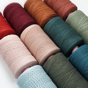 Peut inclure: Une collection de cordes en coton de différentes couleurs, dans des nuances de rouge, orange, vert, bleu et rose. Les cordes sont disposées en cercle, mettant en valeur leur texture et leurs variations de couleurs.