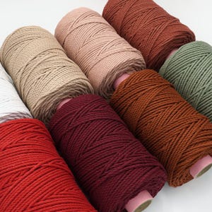 May include: Six spools of cotton rope in various colours, including beige, pink, red, burgundy, orange, and green. The rope is wound tightly around each spool.