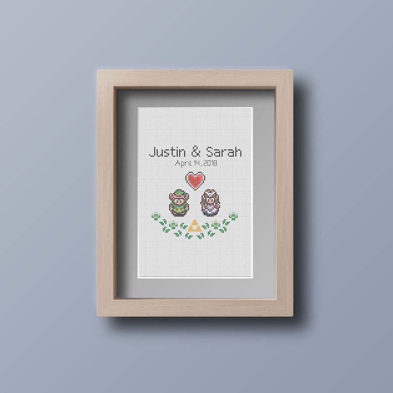 May include: A framed cross-stitch design featuring pixelated characters from the Legend of Zelda video game series. The design includes Link and Princess Zelda, a heart, and the Triforce symbol. The text "Justin & Sarah April 7, 2018" is above the characters.