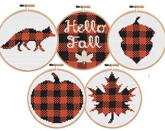May include: Five embroidery hoops with different fall-themed designs. The designs include a fox, a pumpkin, a maple leaf, an acorn, and the words "Hello Fall". All designs are in a black and orange buffalo plaid pattern.