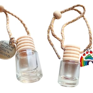 May include: Two car air fresheners with a wooden cap and a glass bottle. One has a silver charm with the text "A piece of my heart lives in Heaven" and the other has a silver charm with a rainbow and paw print.