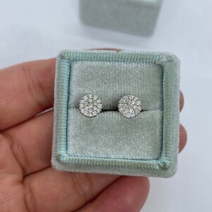 May include: A pair of round diamond earrings in a light blue velvet jewelry box.
