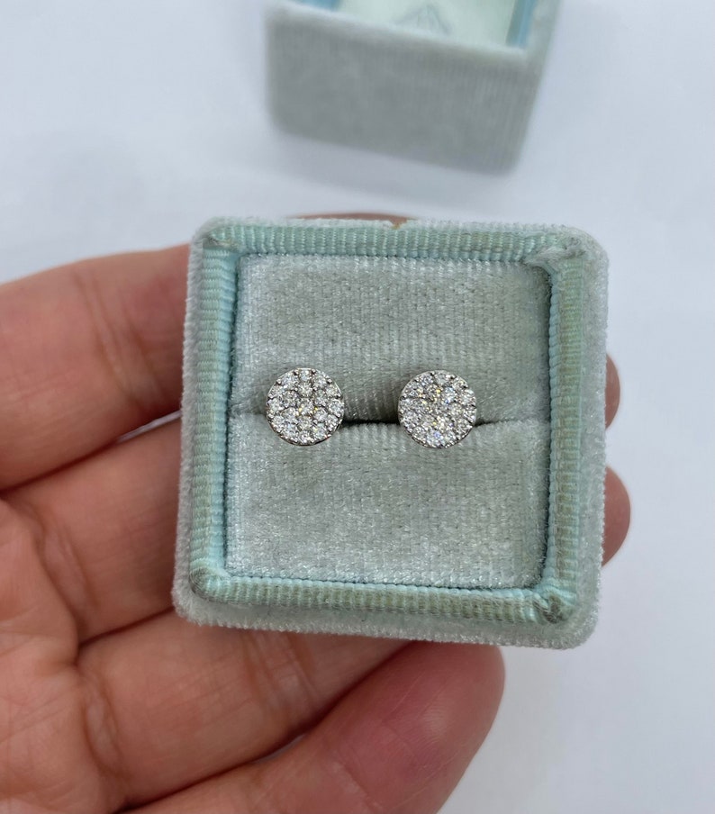 May include: A pair of round diamond earrings in a light blue velvet jewelry box.