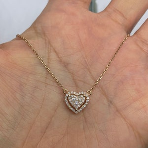 Puede incluir: Un delicado collar de oro con un colgante de coraz&oacute;n doble. El coraz&oacute;n est&aacute; adornado con peque&ntilde;os diamantes brillantes.