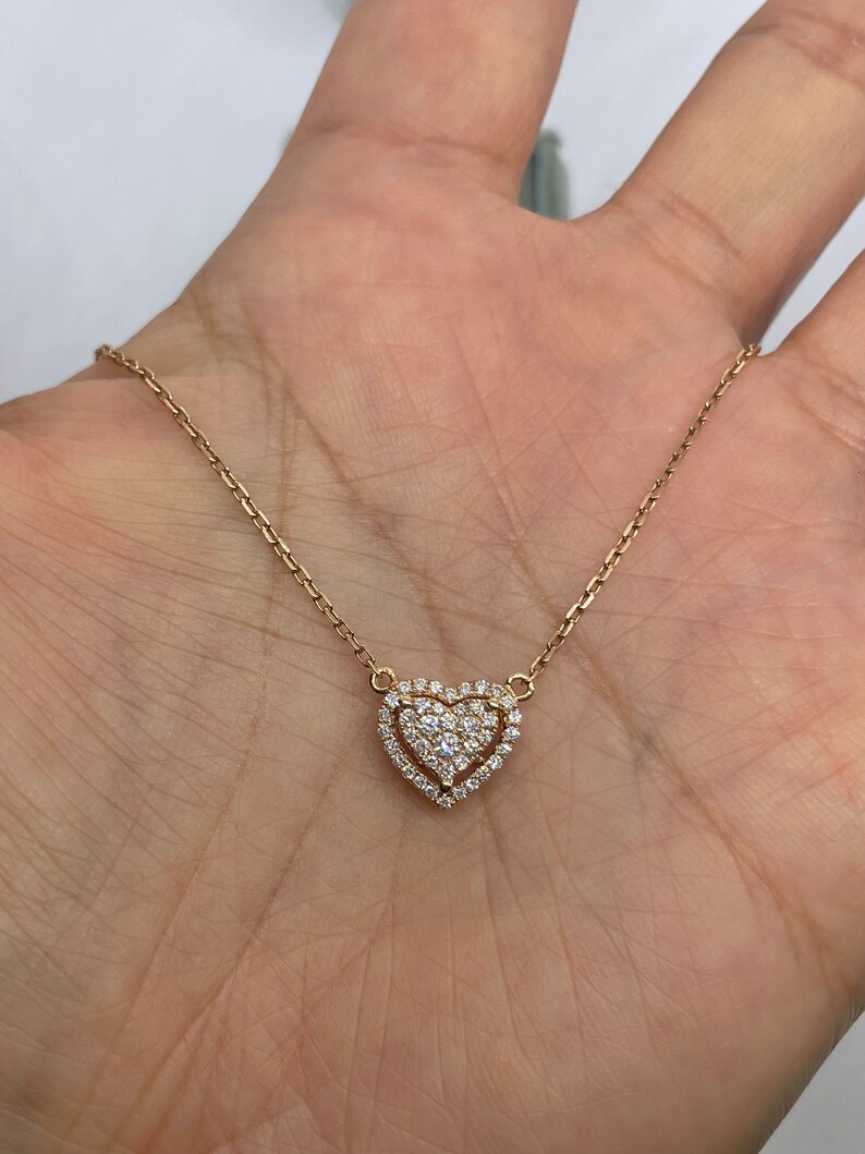 Puede incluir: Un delicado collar de oro con un colgante de coraz&oacute;n doble. El coraz&oacute;n est&aacute; adornado con peque&ntilde;os diamantes brillantes.