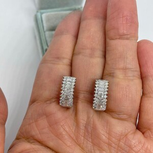 May include: A pair of silver hoop earrings with a row of baguette-shaped diamonds set in each hoop.