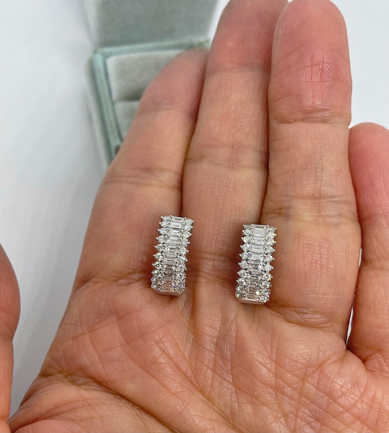 May include: A pair of silver hoop earrings with a row of baguette-shaped diamonds set in each hoop.