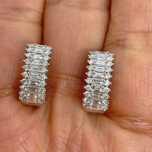 May include: A pair of silver hoop earrings with a double row of baguette and round diamonds.