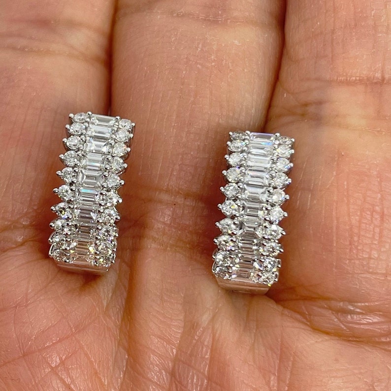 May include: A pair of silver hoop earrings with a double row of baguette and round diamonds.