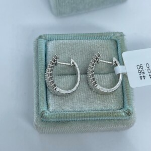 May include: A pair of silver hoop earrings with small diamonds set in the metal. The earrings are in a white velvet box with a tag that reads "44.99 0.96 0.96".