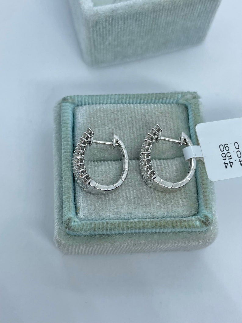 May include: A pair of silver hoop earrings with small diamonds set in the metal. The earrings are in a white velvet box with a tag that reads "44.99 0.96 0.96".