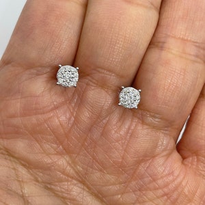 May include: A pair of silver stud earrings with a round, pave-set diamond design.