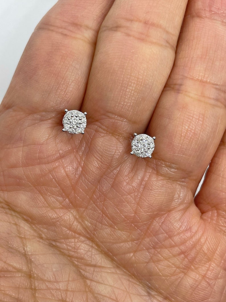 May include: A pair of silver stud earrings with a round, pave-set diamond design.