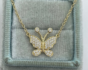 May include: A gold butterfly necklace with clear cubic zirconia stones. The necklace is in a light blue velvet box.