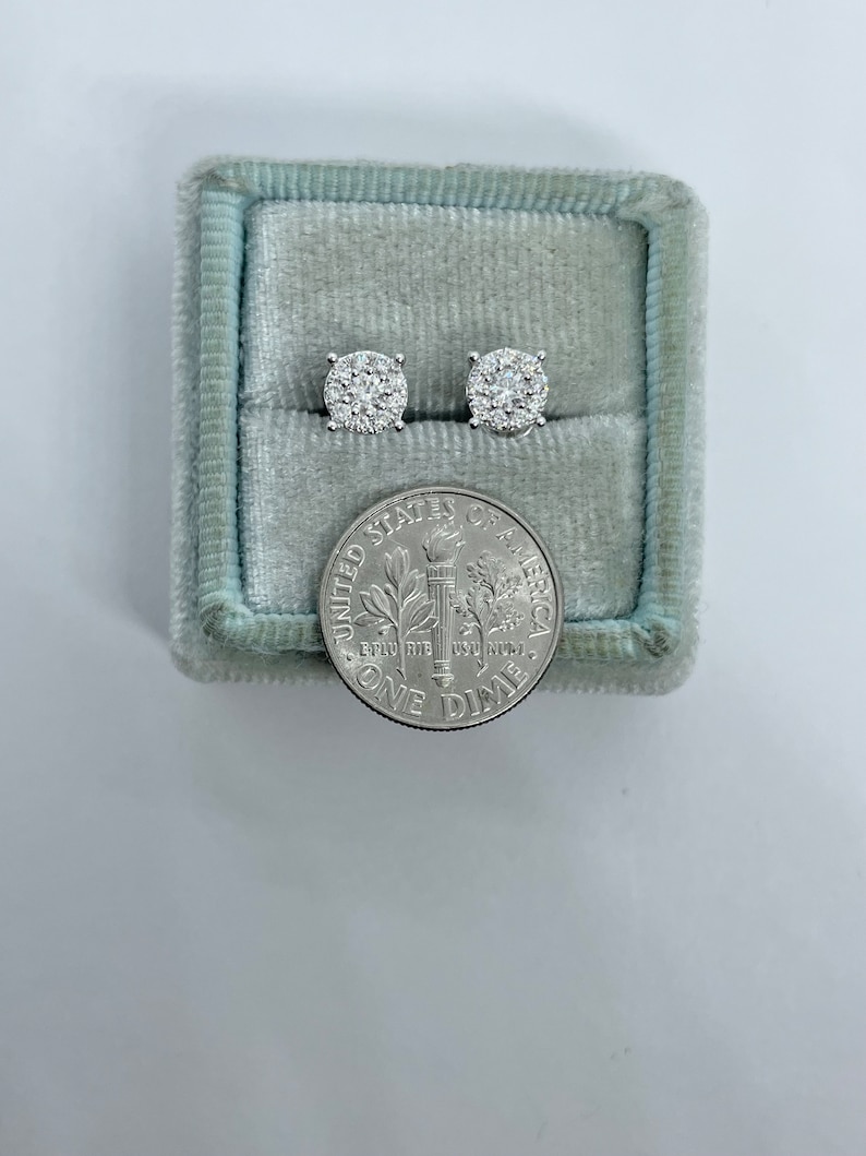 May include: A pair of diamond stud earrings in a blue velvet jewelry box next to a US dime coin.