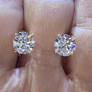 May include: A pair of round diamond earrings with a gold setting. The diamonds are clear and sparkly.