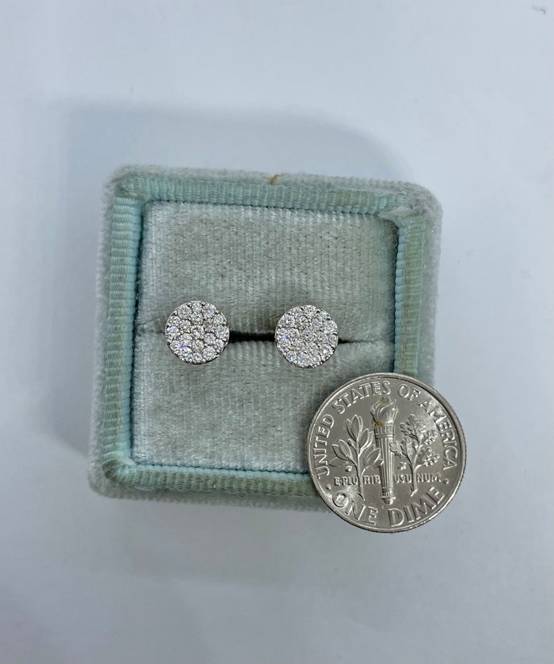May include: A pair of round diamond earrings in a blue velvet jewelry box next to a US dime coin.